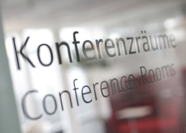 Foto einer sich spiegelnden Glastür, die mit „Konferenzräume“ beschriftet ist