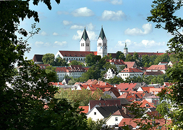 Foto einer kleinen Stadt mit roten Dächern, die von grünen Pflanzen eingerahmt ist 