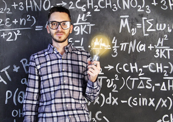 Foto eines Wisseschaftler mit einer leuchtenden Glühbirne in der Hand, vor einer Tafel mit mathematischen Formeln