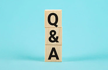 Als Holzbausteine stehen ein "Q", ein "&" und ein "A" aufeinander