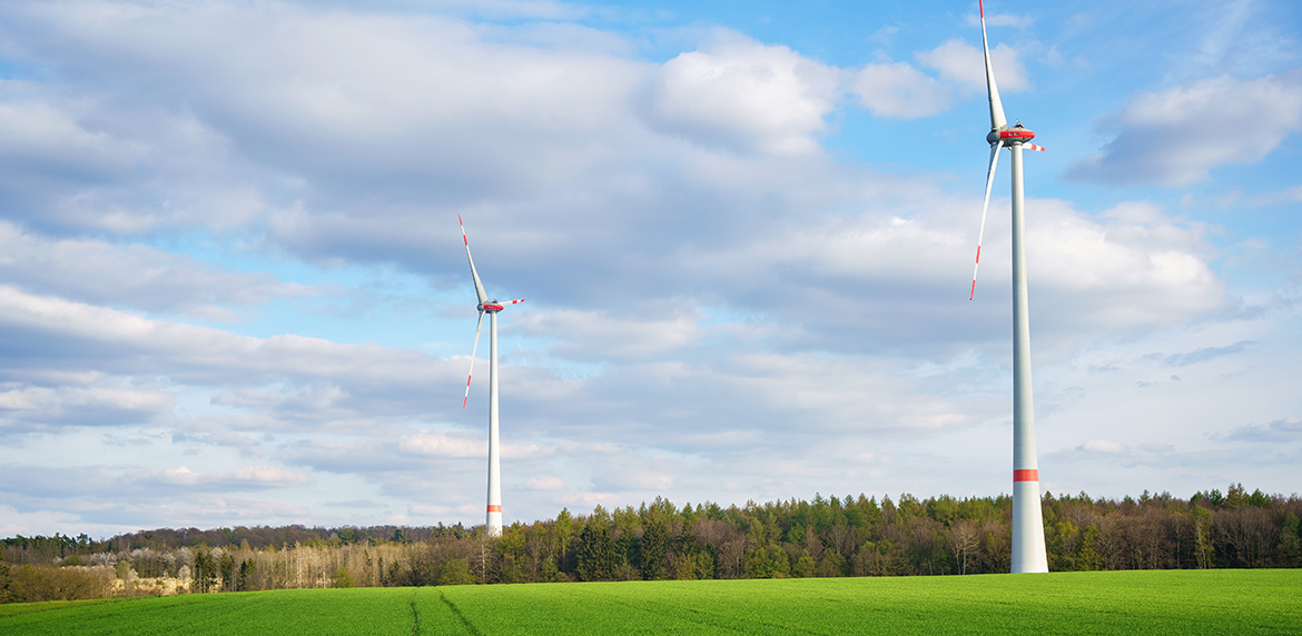 Zwei Windräder stehen in einer Landschaft in Bayern.